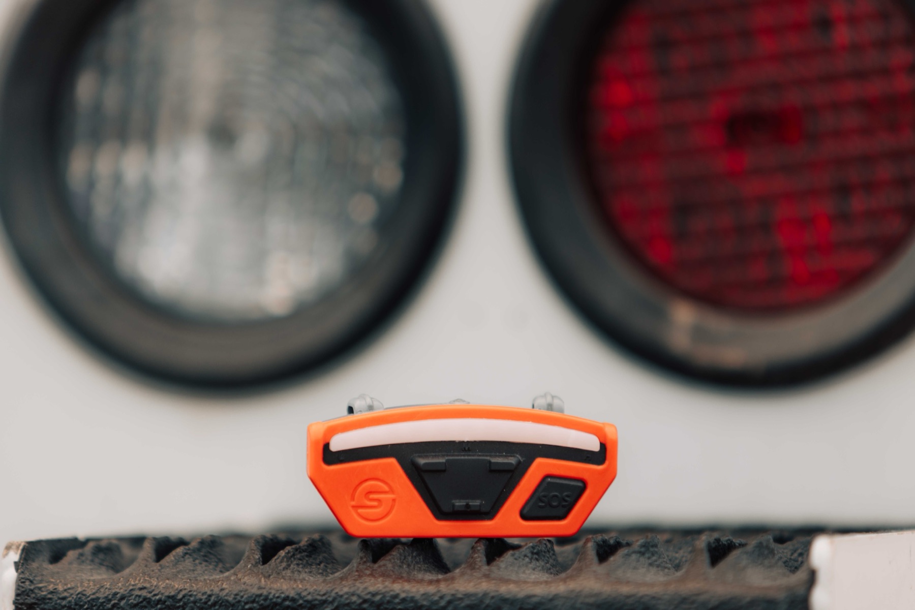 Compass Pro device resting on a truck bumper, showing the LED light bar and SOS button