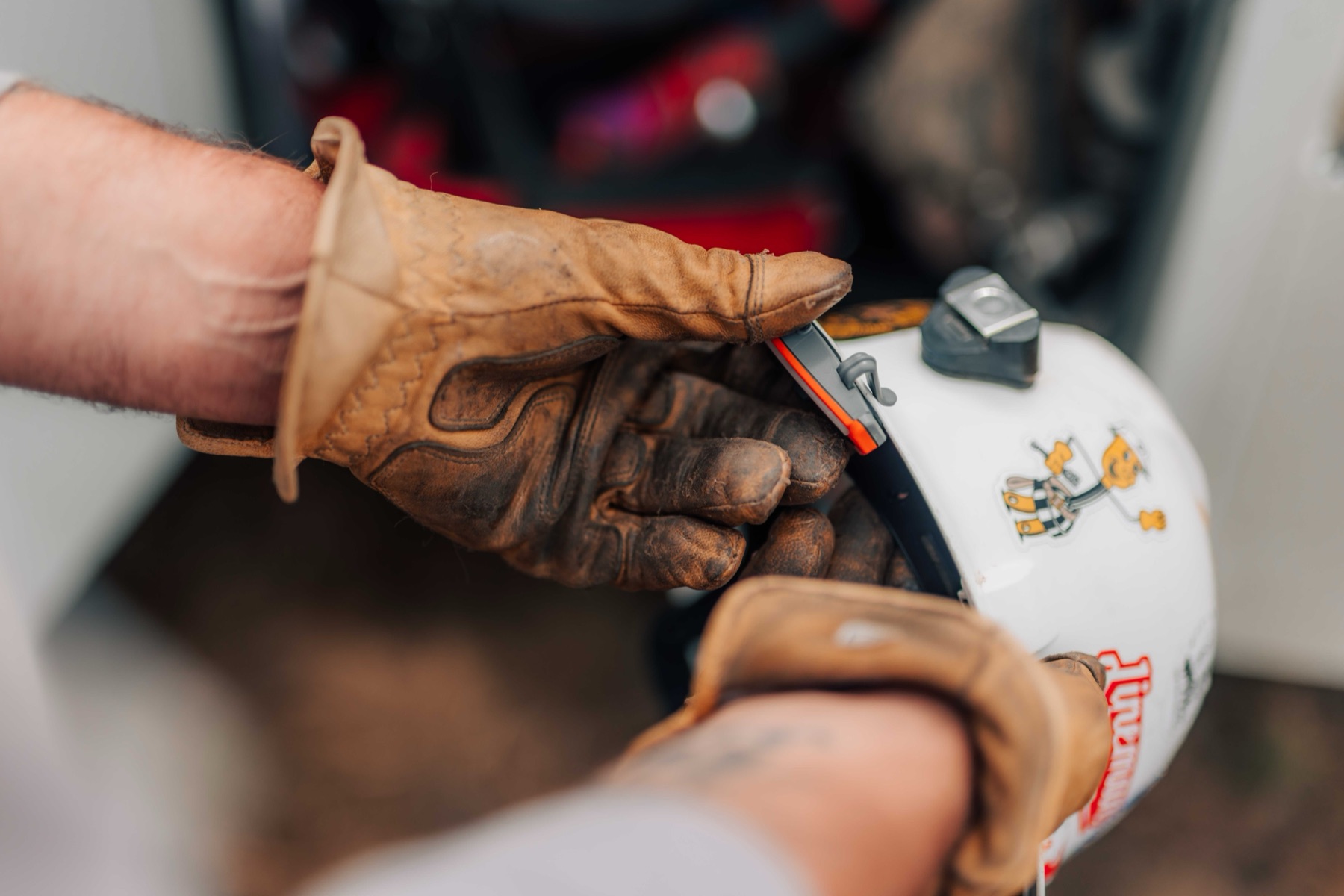 Gloved hands clipping a Compass device onto a hard hat brim